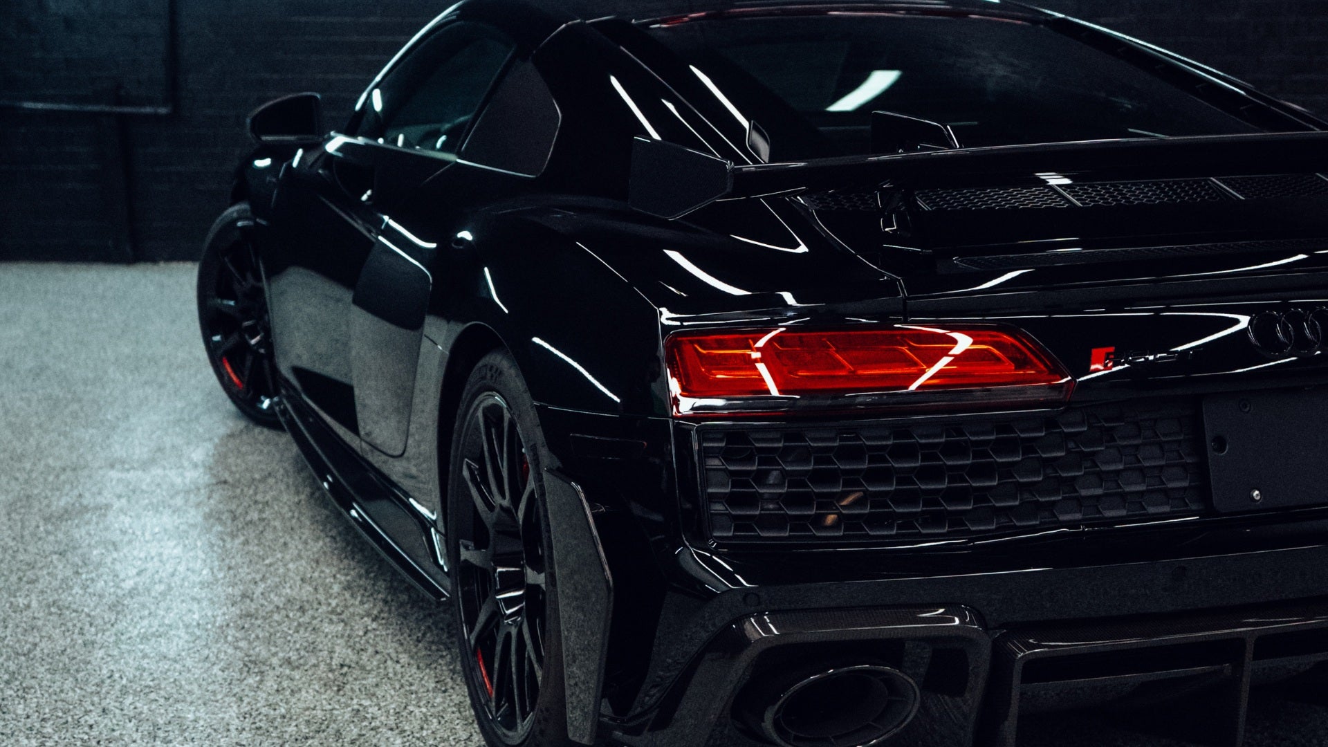 Black sports car with red taillights in a dark setting