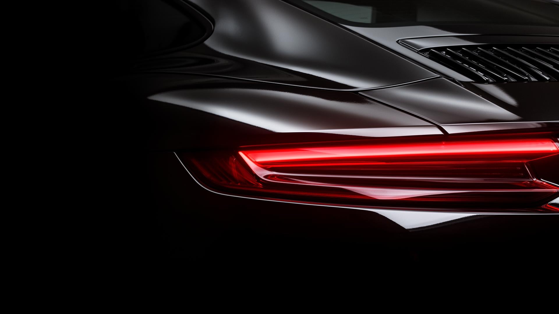 Rear view of a sleek black sports car showcasing its aerodynamic design and distinctive taillights.